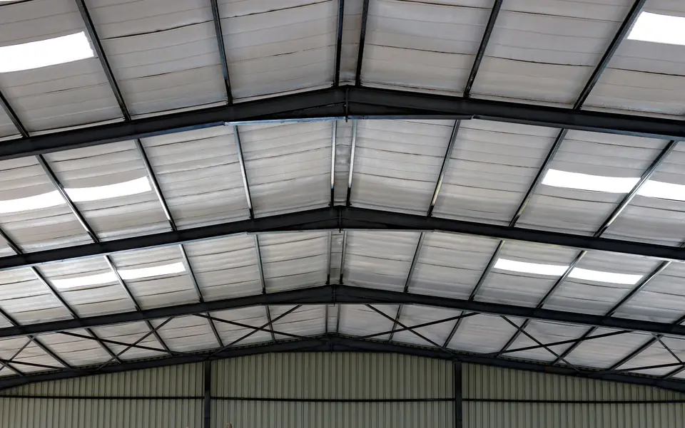Inside a steel-frame building with faced insulation between the roof purlins and metal wall panels